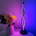 Decorative lamp with wavy design next to a vase of flowers on a table.